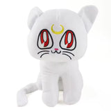Artemis white cat plush with red embroidered eyes, yellow crescent moon, and curled tail