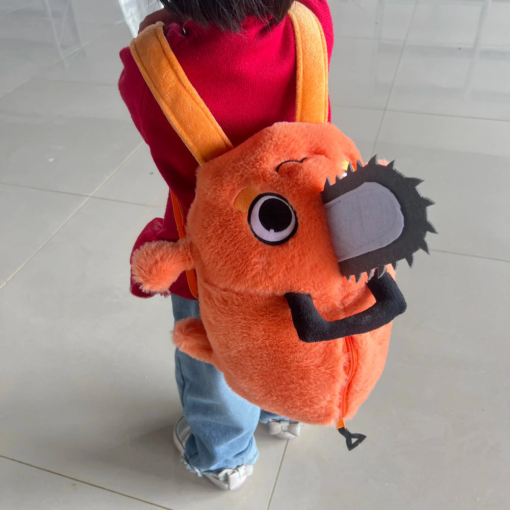 Orange Pochita plush backpack worn with two shoulder straps, a gray chainsaw detail and a zippered opening