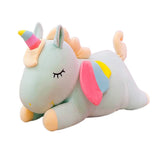 Green sleeping unicorn plush with closed eyes, rainbow horn, and colorful wings