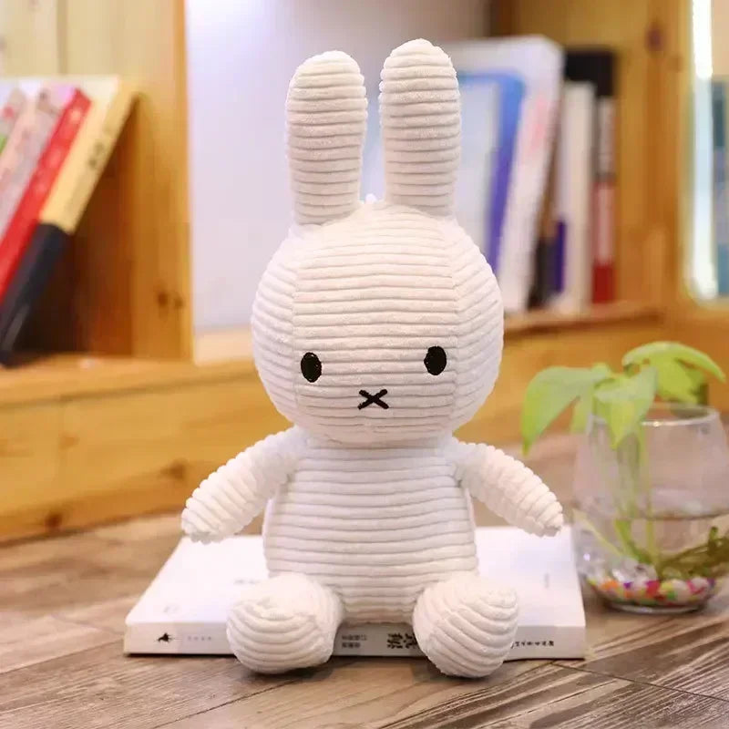 White ribbed Miffy bunny plush with upright ears, seated on a book