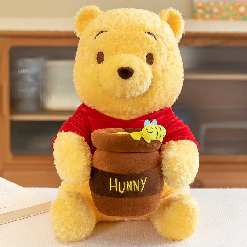Winnie the Pooh Hunny Pot Plush — seated yellow bear holding a brown pot with a bee