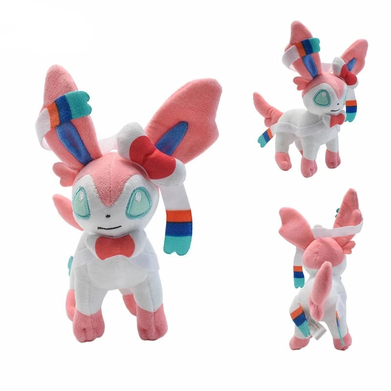 Front, side, and back views of standing Sylveon Pokémon plush with pink ears and colorful ribbons