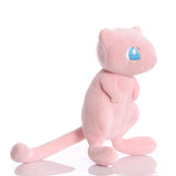 Angled view of pink Mew plush showing its blue eyes, wide feet, and curved tail