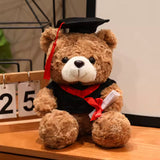Brown graduation teddy bear with black cap and red trim, 25 cm
