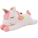 White sleeping unicorn plush with closed eyes, rainbow horn, and colorful wings
