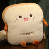 Cream toast plush pillow with brown crust, little arms and feet, and an embroidered I'M TOAST design